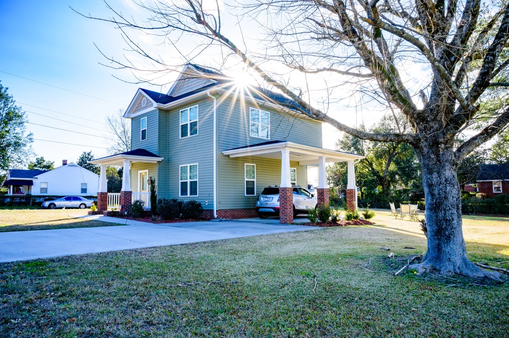 Two-story house with a car parked under the carport on a sunny day